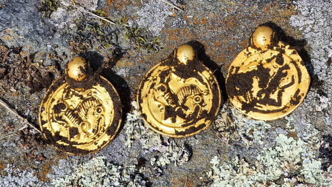 Trois pendentif en or, en forme de pièces de monnaie (bractéates), mises au jour sur l'île de Rennesøy en Norvège, vieux de 1500 ans.